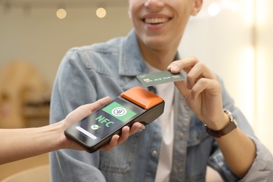 Image of Payment terminal with NFC system. Client using credit card to pay for service indoors, closeup