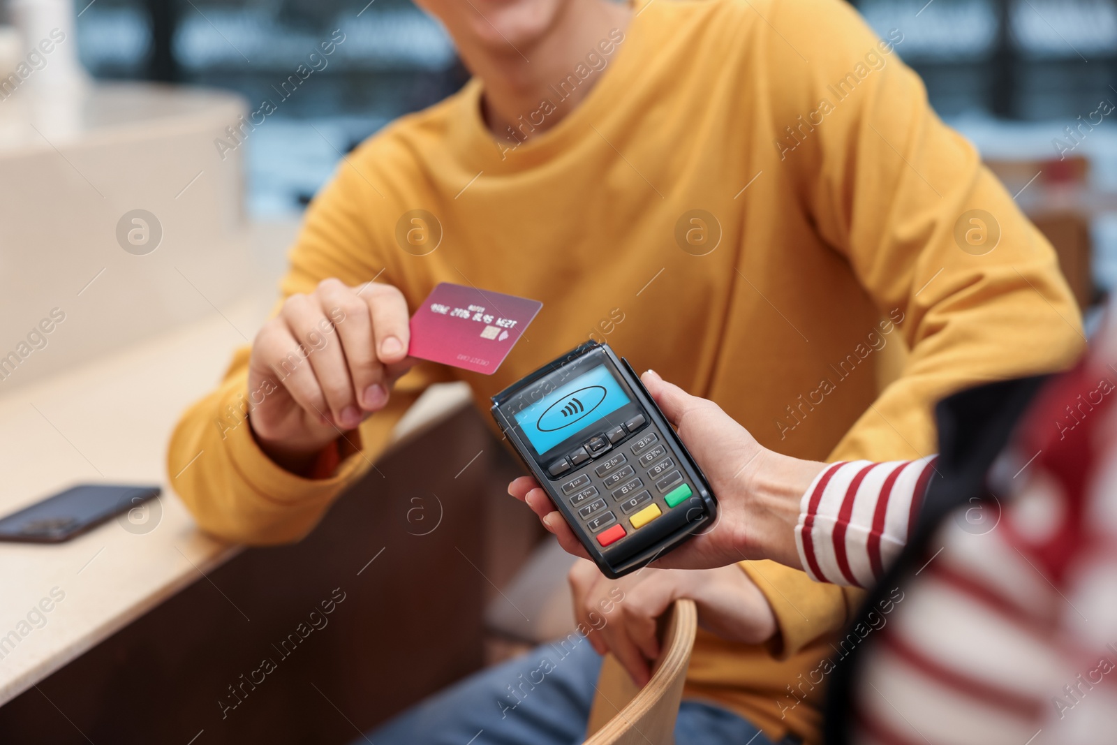 Payment terminal with NFC system. Client using credit card to pay for service indoors, closeup Image of Payment terminal with NFC system. Client using credit card to pay for service indoors, closeup