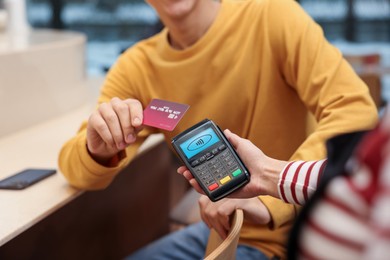 Image of Payment terminal with NFC system. Client using credit card to pay for service indoors, closeup