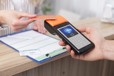 Image of Payment terminal with NFC system. Client using credit card to pay for service indoors, closeup