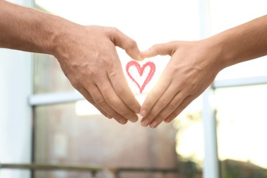 Image of Man and woman making heart with their hands indoors, closeup