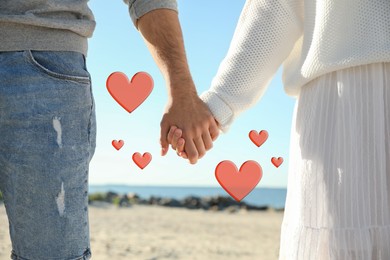 Image of Lovely couple holding hands on beach, closeup. Drawn hearts near them