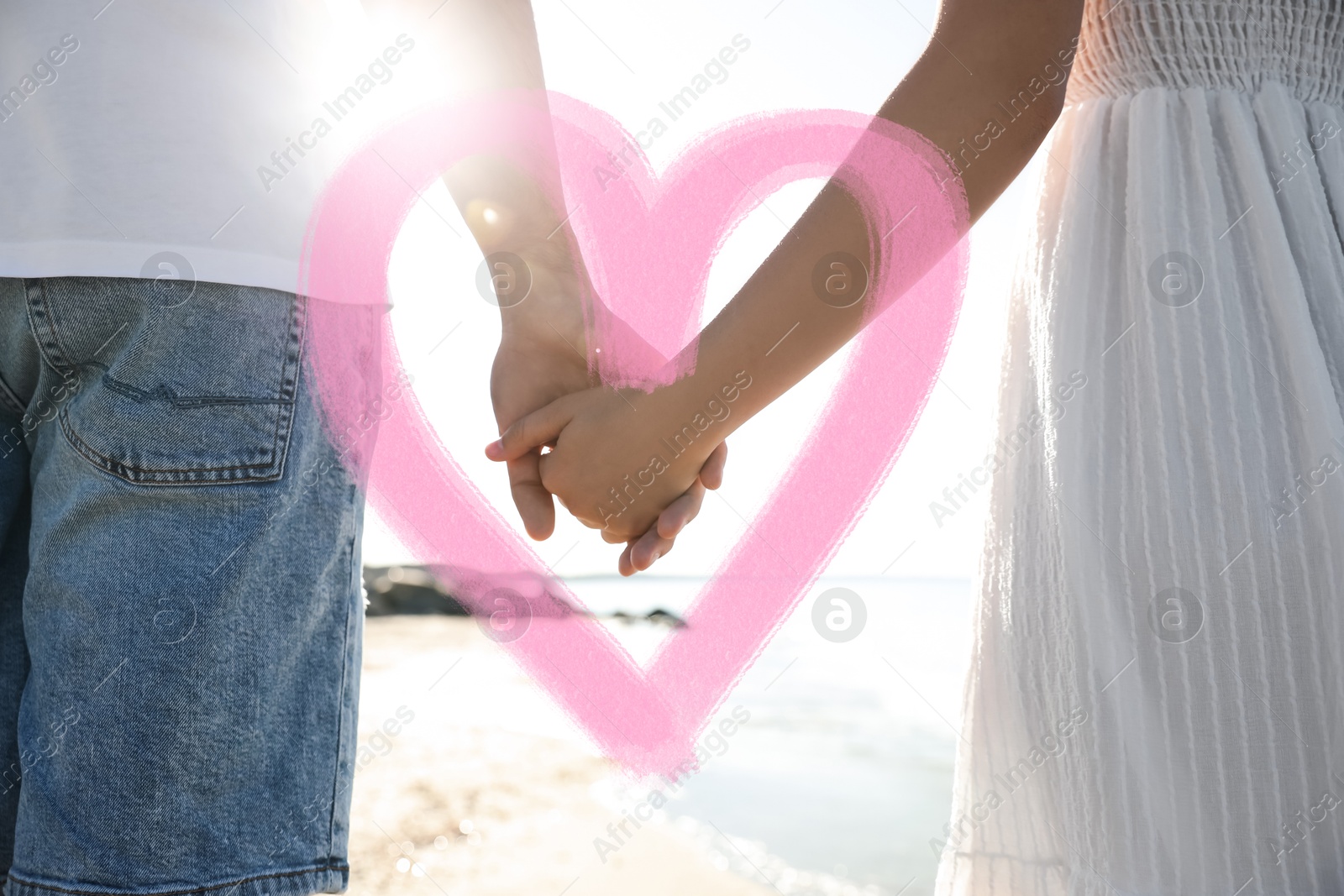 Lovely couple on beach, closeup. Drawn heart around their hands Image of Lovely couple on beach, closeup. Drawn heart around their hands