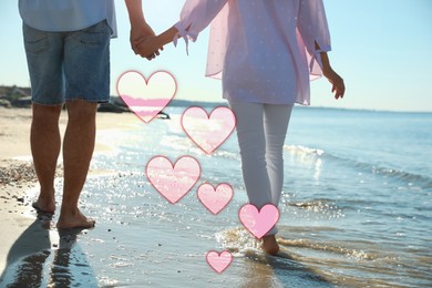 Image of Lovely couple holding hands and walking on beach, closeup. Drawn hearts near them