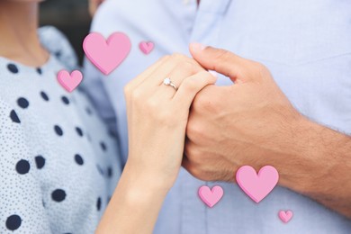 Image of Lovely engaged couple holding hands, closeup. Drawn hearts near them