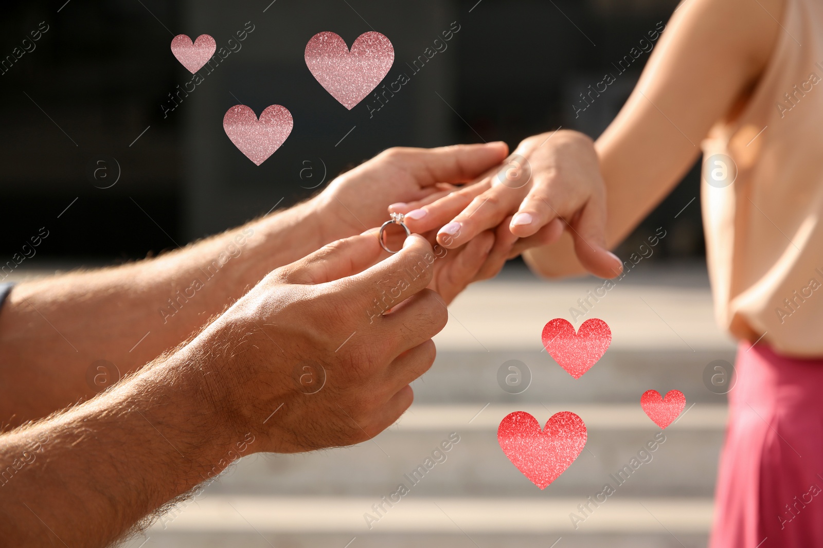 Man putting engagement ring on his girlfriend's finger outdoors, closeup. Drawn hearts near them Image of Man putting engagement ring on his girlfriend's finger outdoors, closeup. Drawn hearts near them