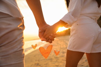 Image of Lovely couple holding hands and walking on beach, closeup. Drawn hearts near them