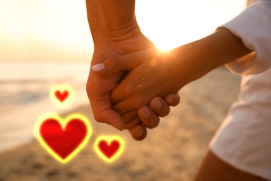 Image of Lovely couple holding hands on beach, closeup. Drawn hearts near them
