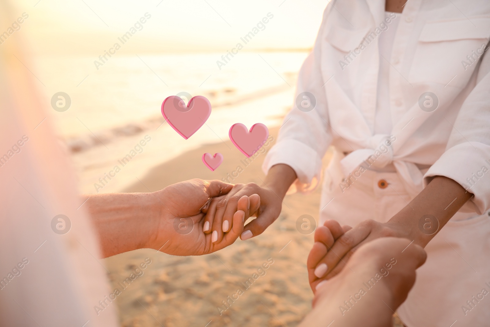 Lovely couple holding hands on beach, closeup. Drawn hearts near them Image of Lovely couple holding hands on beach, closeup. Drawn hearts near them