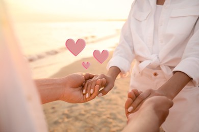 Image of Lovely couple holding hands on beach, closeup. Drawn hearts near them