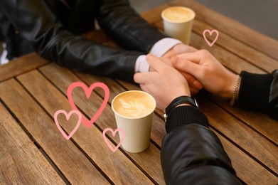 Image of Lovely couple holding hands while drinking coffee at wooden table, closeup. Drawn hearts near them