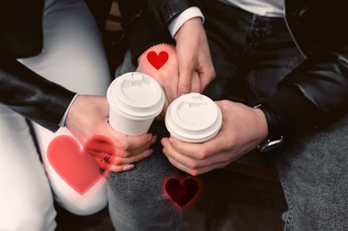 Image of Lovely couple holding hands while drinking coffee outdoors, closeup. Drawn hearts near them