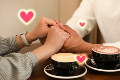 Image of Lovely couple holding hands while drinking coffee in cafe, closeup. Drawn hearts near them
