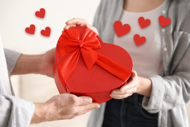 Image of Lovely couple with gift box indoors, closeup. Drawn hearts near them