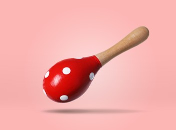 Image of Toy maraca in air on pink background. Child's musical instrument