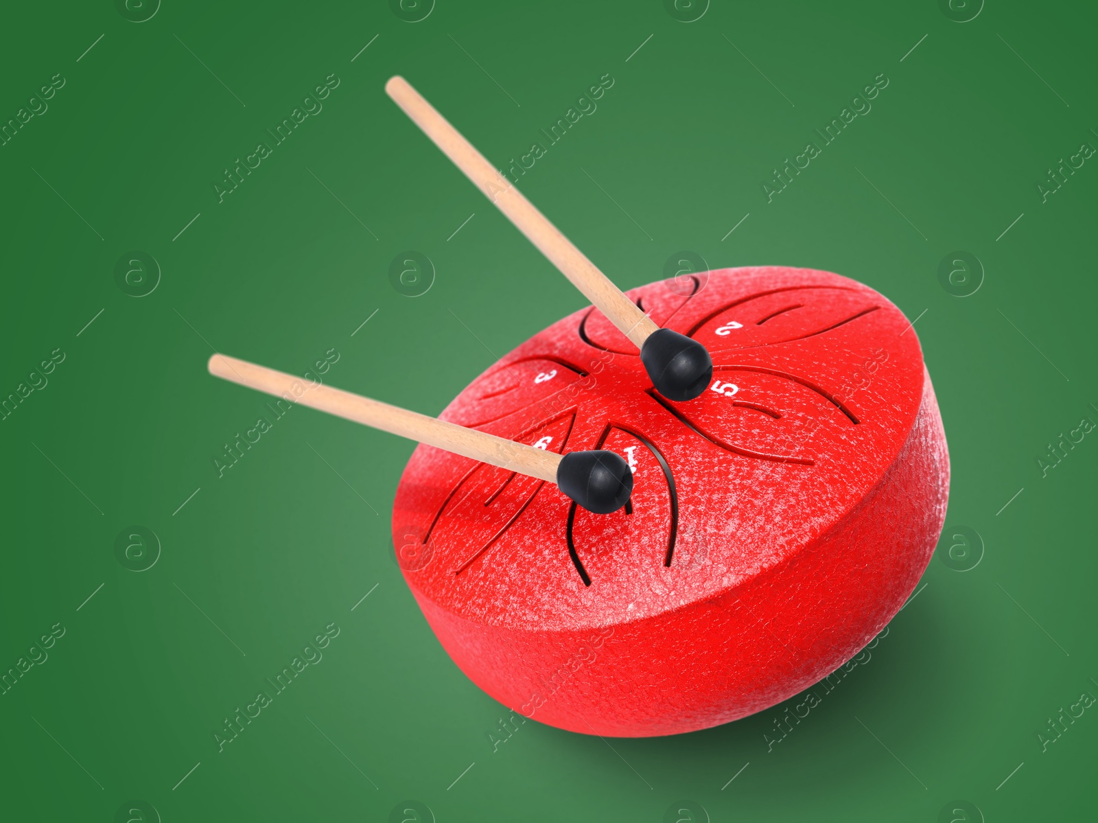 Red toy tongue drum in air on green background. Child's musical instrument Image of Red toy tongue drum in air on green background. Child's musical instrument