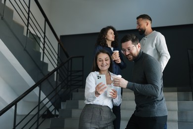 Photo of Colleagues with coffee on stairs in office during break