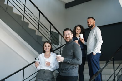 Photo of Colleagues with coffee on stairs in office during break
