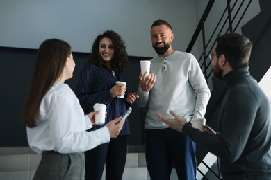 Photo of Colleagues with coffee on stairs in office during break