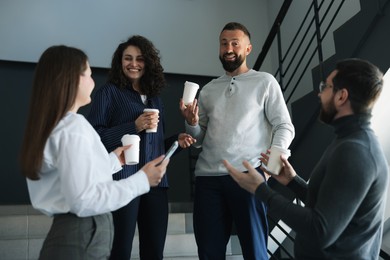 Photo of Colleagues with coffee on stairs in office during break