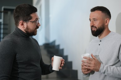 Photo of Colleagues with coffee on stairs in office during break