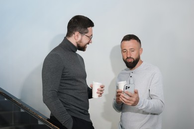 Photo of Colleagues with coffee on stairs in office during break