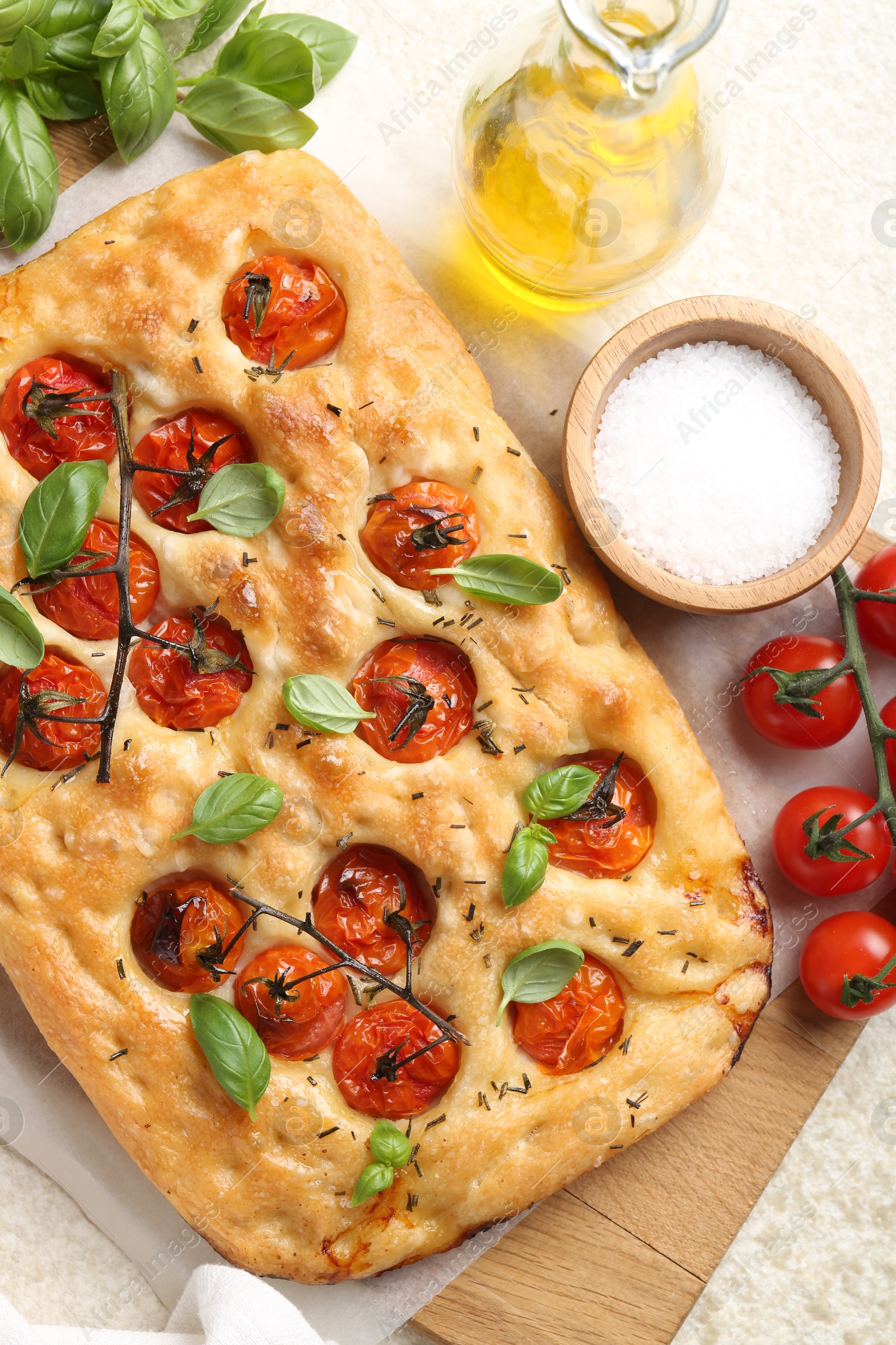 Delicious focaccia with tomatoes, spices and oil on beige table, flat lay Photo of Delicious focaccia with tomatoes, spices and oil on beige table, flat lay