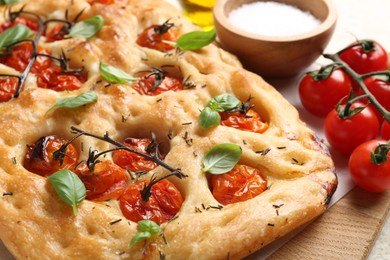 Photo of Delicious focaccia with tomatoes and spices on table, closeup