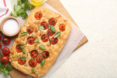 Photo of Delicious focaccia with tomatoes and spices on beige textured table, flat lay. Space for text