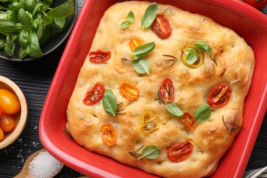 Photo of Delicious focaccia with tomatoes and spices in baking dish on table, flat lay