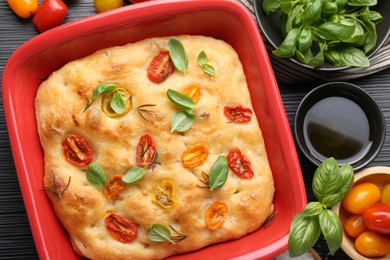 Photo of Delicious focaccia with tomatoes, spices and oil on table, flat lay