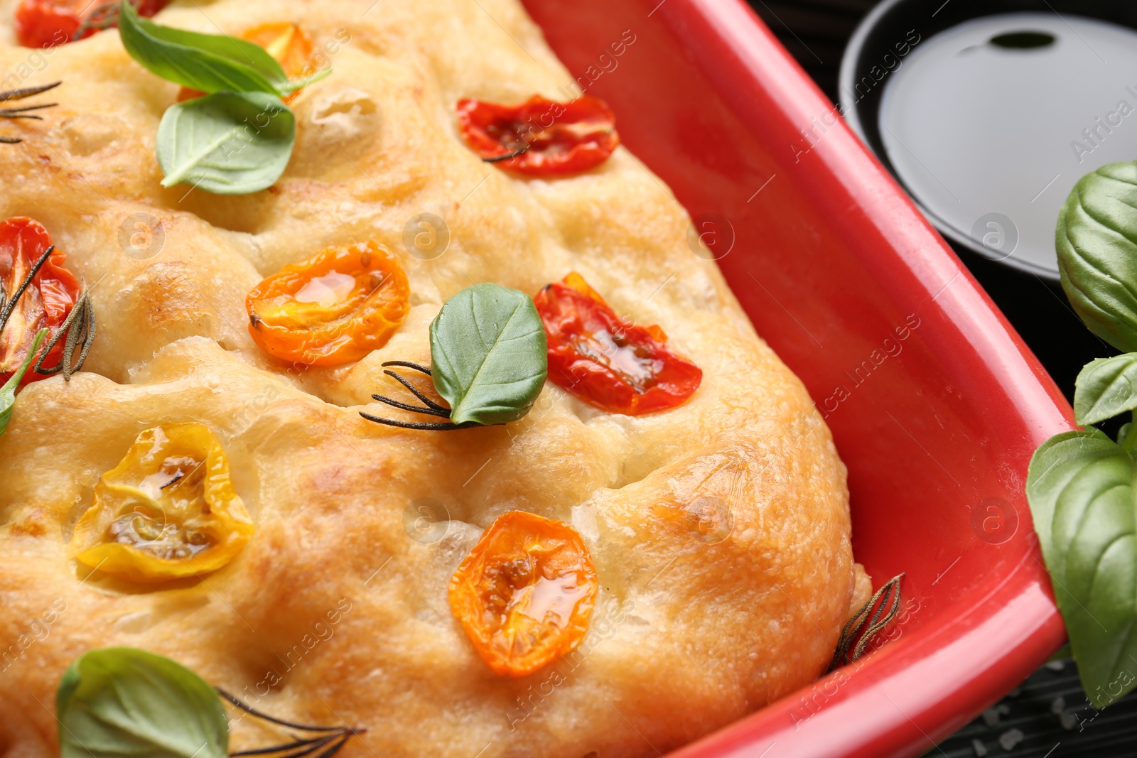 Delicious focaccia with tomatoes and spices in baking dish on table, closeup Photo of Delicious focaccia with tomatoes and spices in baking dish on table, closeup