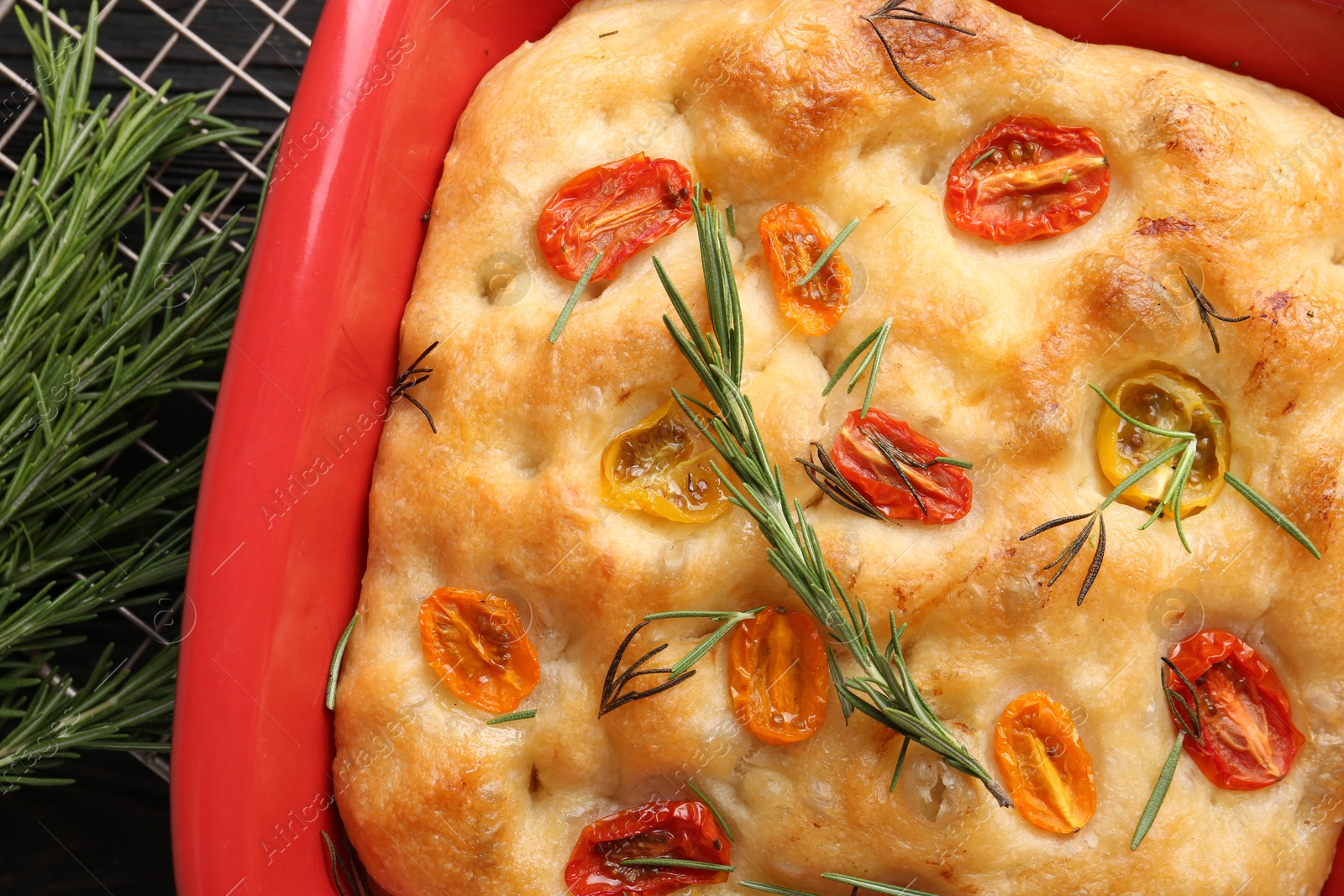 Delicious focaccia with tomatoes and rosemary in baking dish on table, top view Photo of Delicious focaccia with tomatoes and rosemary in baking dish on table, top view