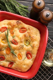 Photo of Delicious focaccia with tomatoes, spices and oil on table, flat lay