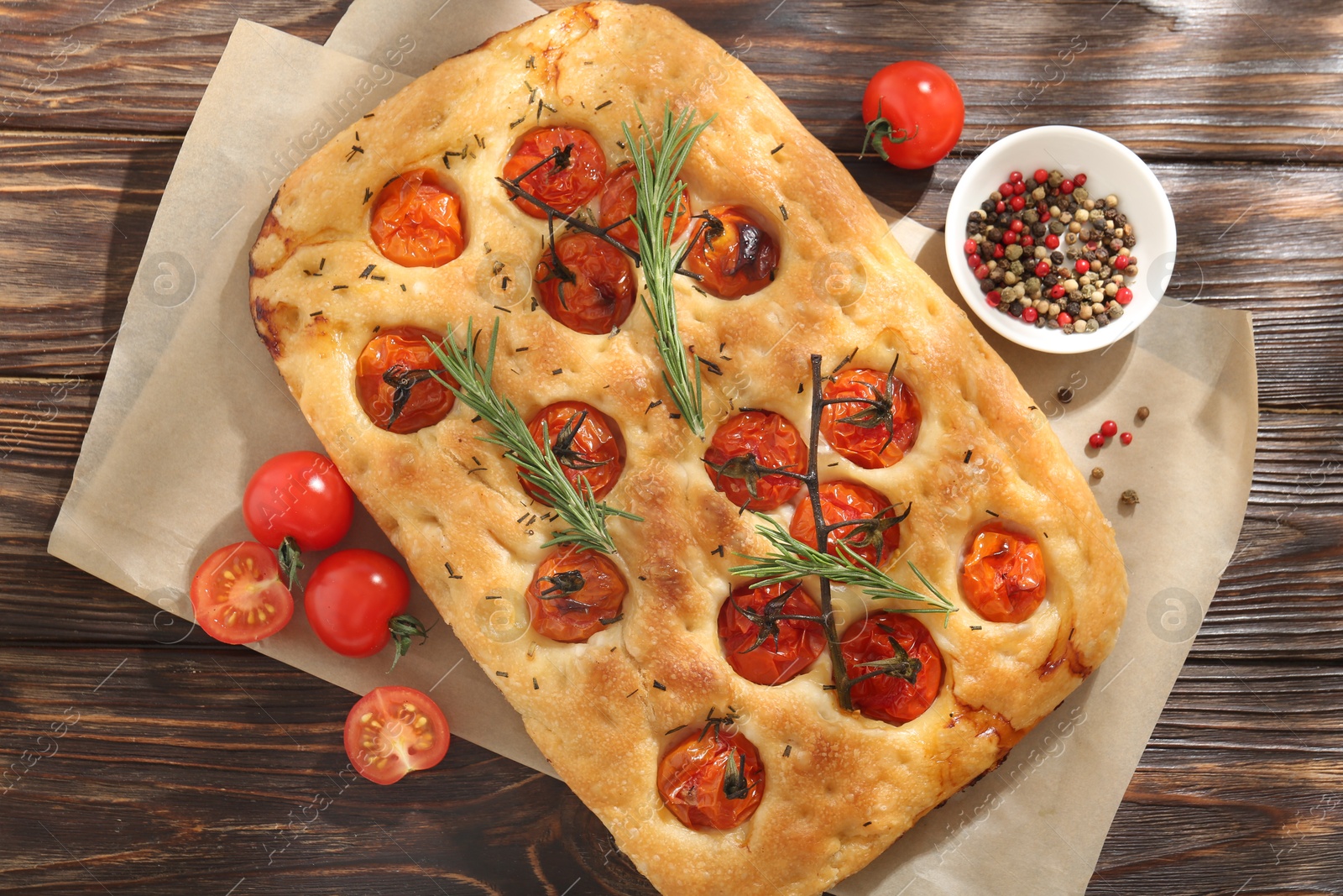 Delicious focaccia with tomatoes and spices on wooden table, flat lay Photo of Delicious focaccia with tomatoes and spices on wooden table, flat lay