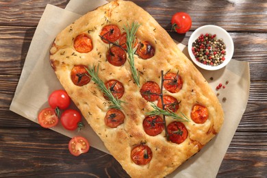 Photo of Delicious focaccia with tomatoes and spices on wooden table, flat lay