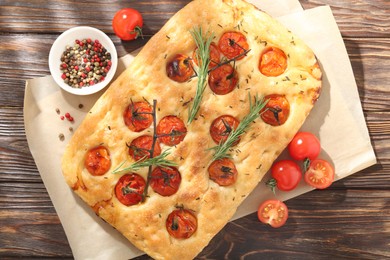 Photo of Delicious focaccia with tomatoes and spices on wooden table, flat lay
