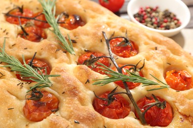 Photo of Delicious focaccia with tomatoes and spices on table, closeup