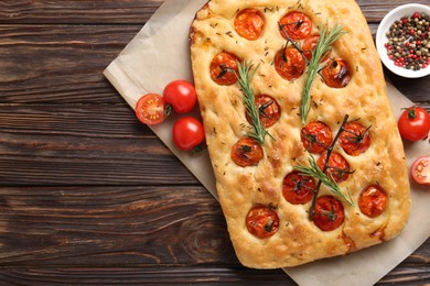 Photo of Delicious focaccia with tomatoes and spices on wooden table, flat lay. Space for text