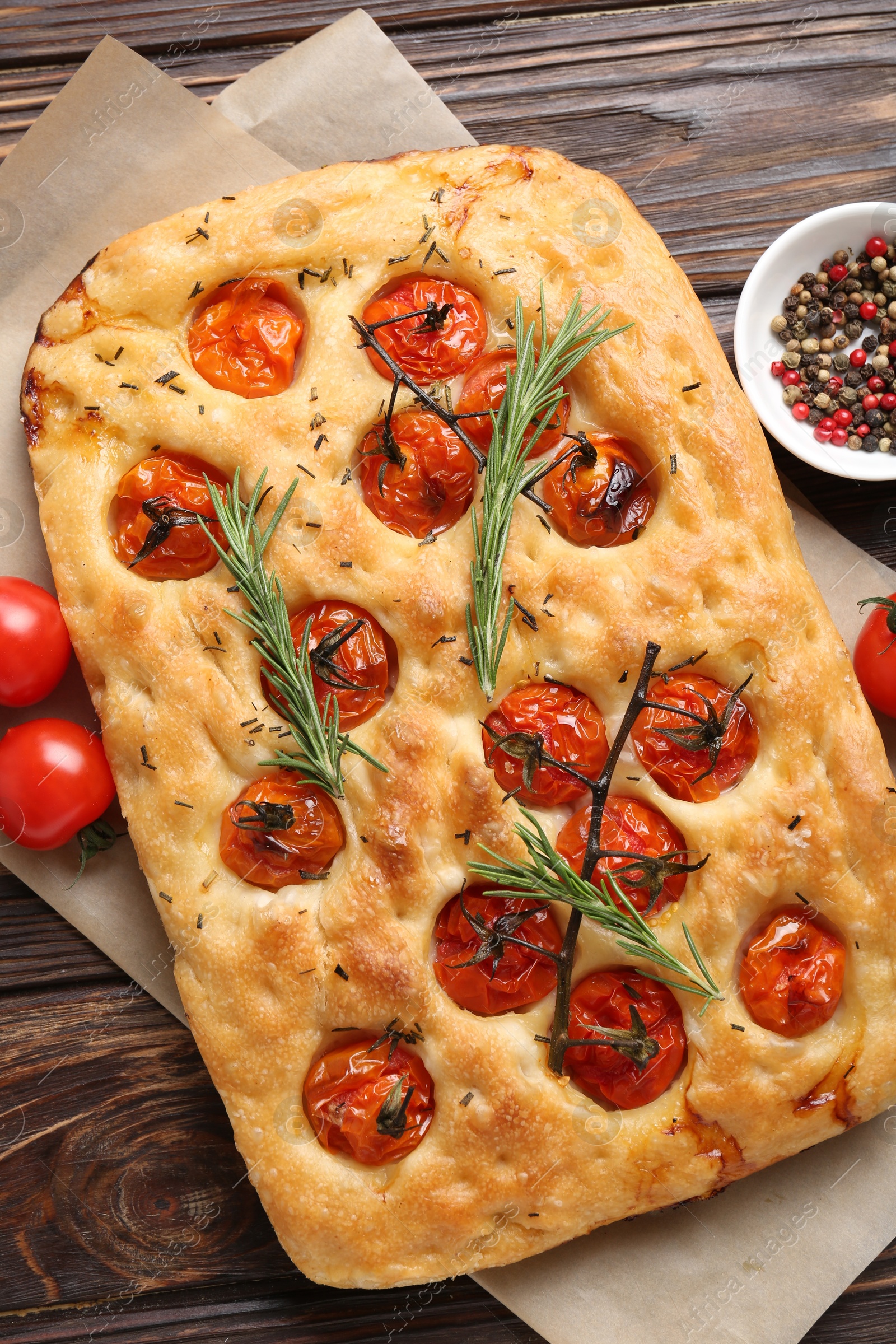 Delicious focaccia with tomatoes and spices on wooden table, flat lay Photo of Delicious focaccia with tomatoes and spices on wooden table, flat lay