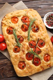Photo of Delicious focaccia with tomatoes and spices on wooden table, flat lay