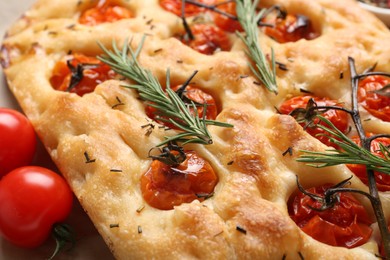 Photo of Delicious focaccia with tomatoes and spices on table, closeup