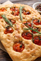 Photo of Delicious focaccia with tomatoes and spices on table, closeup