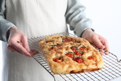 Photo of Woman holding delicious focaccia with tomatoes and spices on light background, closeup