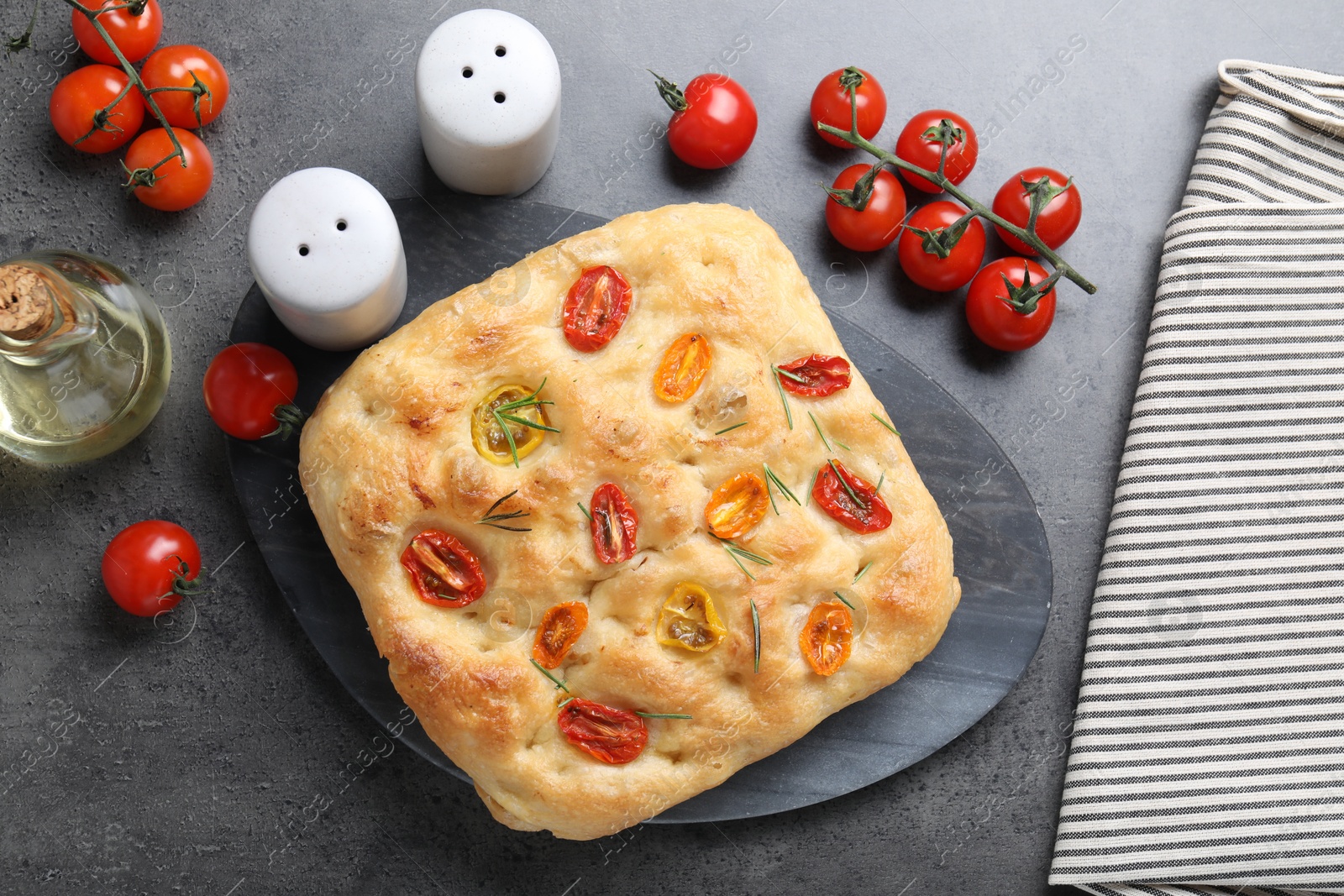 Delicious focaccia with tomatoes, spices and oil on gray textured table, flat lay Photo of Delicious focaccia with tomatoes, spices and oil on gray textured table, flat lay