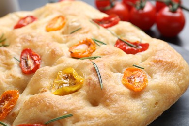 Photo of Delicious focaccia with tomatoes and rosemary on table, closeup