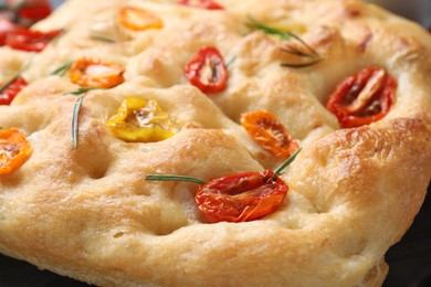 Photo of Delicious focaccia with tomatoes and rosemary on table, closeup