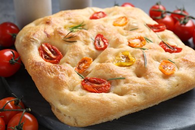 Photo of Delicious focaccia with tomatoes and rosemary on table, closeup
