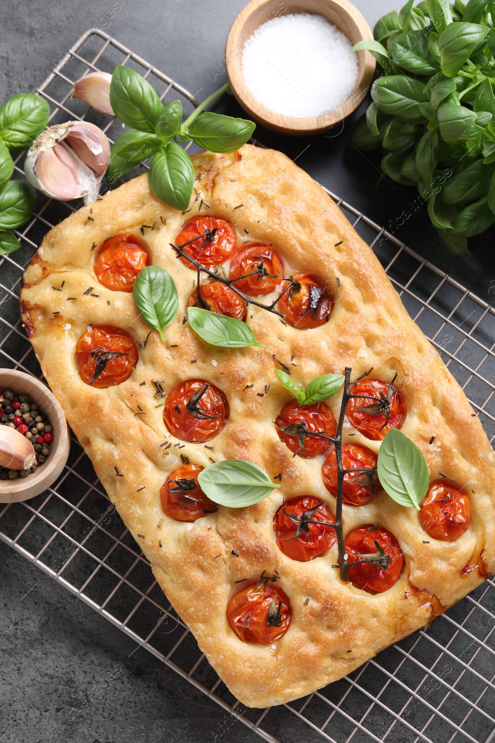 Delicious focaccia with tomatoes and spices on gray table, flat lay Photo of Delicious focaccia with tomatoes and spices on gray table, flat lay