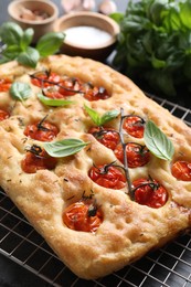 Photo of Delicious focaccia with tomatoes and spices on table, closeup